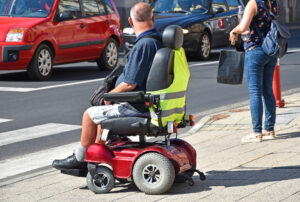 Man in an electric wheelchair cross the pedestrian lane