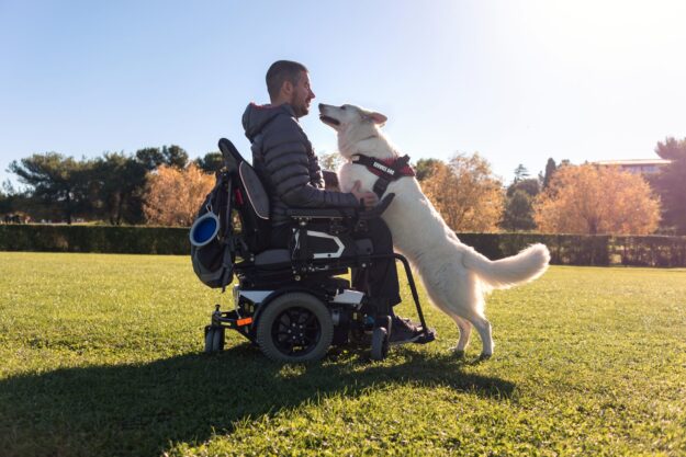 An image featuring a disabled man in an electric wheelchair, accompanied by his loyal dog.