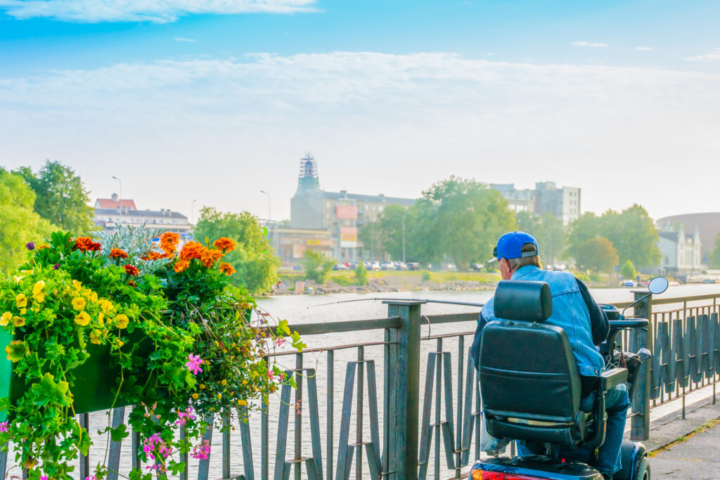 Senior using a mobility scooter outdoors in Ireland, navigating a park with ease.
